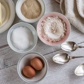 A table with ingredients for a baking project laid out, butter, sugar and flour, and two eggs.