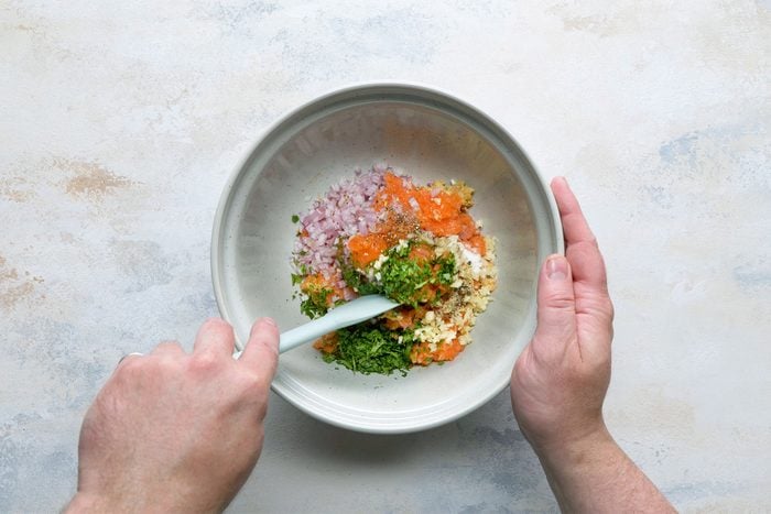 Overhead shot of bowl; add shallot; cilantro; soy sauce; honey garlic; salt and pepper; mix well; spatula; white marble background;