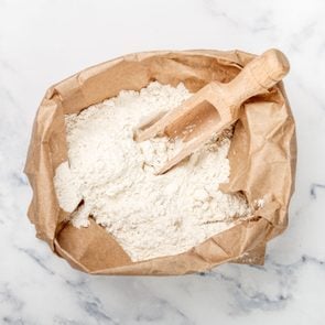 Wheat Flour And A Wooden Scoop In A Paper Bag On A Marble Table